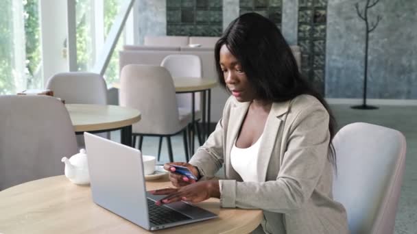 Mujer negra ingresa número de tarjeta de crédito para pagar en línea en la cafetería — Vídeos de Stock