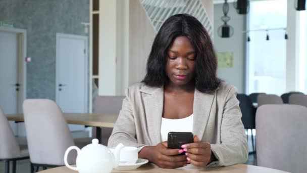 Femme noire textos message sur smartphone à la table dans le café — Video