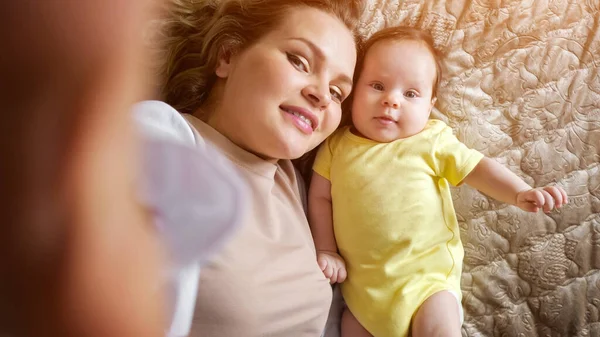 Jolie jeune mère aux cheveux bouclés prend une photo de sa fille — Photo