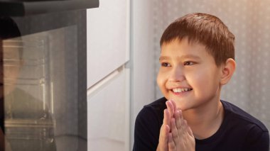 Çocuk yemek beklerken oturur ve fırına bakar.