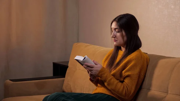 Señora interesada con el pelo largo sostiene libro de papel y lee —  Fotos de Stock