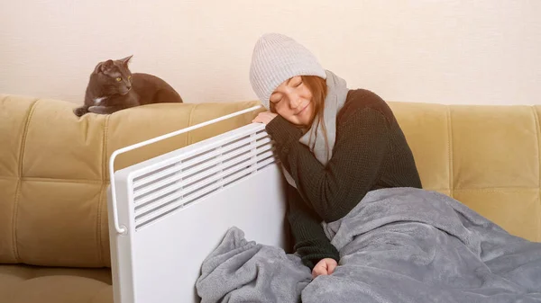 Congelato signora si appoggia su riscaldatore seduta vicino gatto su morbido divano — Foto Stock