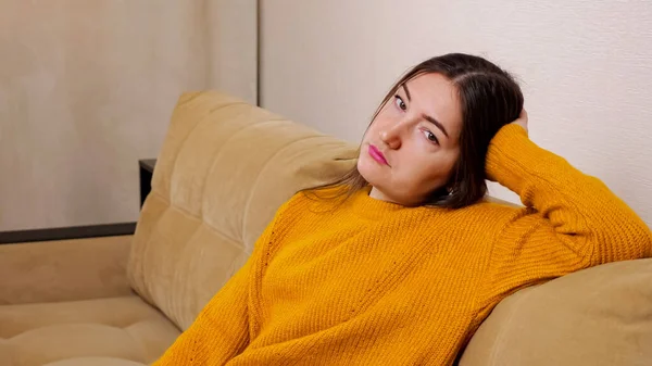 Депрессивная брюнетка с длинными распущенными волосами сидит на диване — стоковое фото