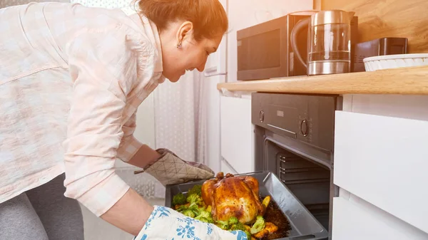 Mujer saca comida preparada del horno, pollo con verduras — Foto de Stock