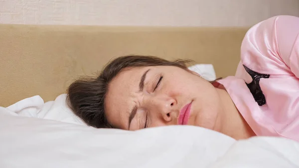 Señora se encuentra en la cama cerrando la oreja con almohada — Foto de Stock