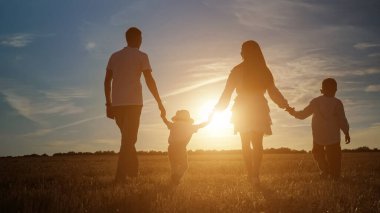 Çocuklu aile gün batımında tarlalar boyunca yürür.