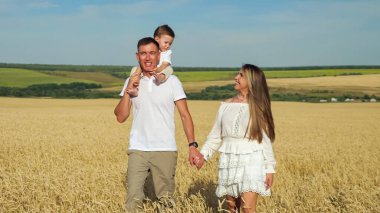 Oğlu olan genç bir aile yazın olgun buğday tarlalarında yürür.