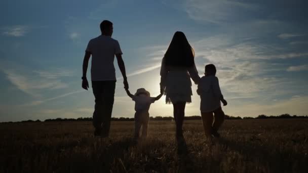 Οικογένεια με παιδιά περπατά κατά μήκος των αγρών στο πίσω μέρος δύοντας ήλιο — Αρχείο Βίντεο