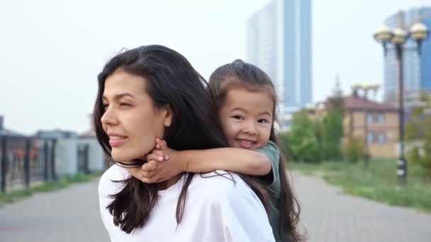 Frau gibt kleinem Mädchen Huckepack-Fahrt am Stadtwasserufer — Stockvideo