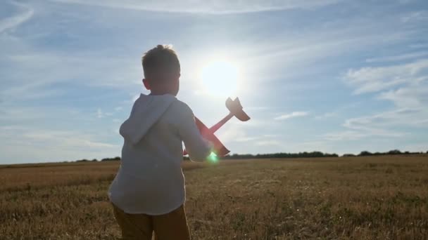 Junge läuft mit Spielzeugflugzeug in der Hand in Feld und fliegt Flugzeug — Stockvideo