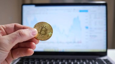 Dizüstü bilgisayarın arka planında şifreli para tutan erkek el grafiği gösteriyor