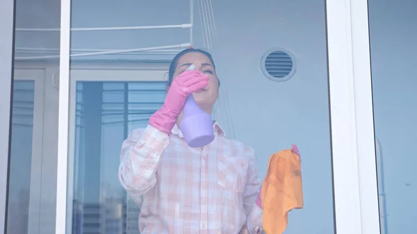 Молодая женщина моет окно в перчатках с тряпкой, — стоковое фото