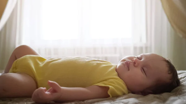 เด็กสาวในเสื้อผ้าสีเหลืองนอนบนเตียงกับหน้าต่าง — ภาพถ่ายสต็อก