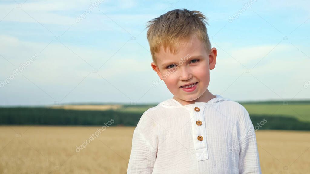 Young boy with bunch of ripe wheat spicules in yellow field