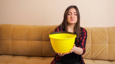 Üzgün kadın, tavandan aşağı akan suyu topluyor.