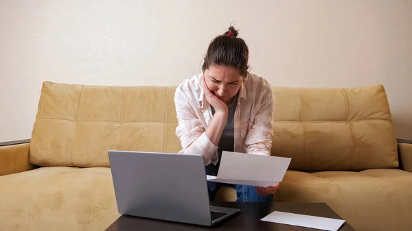 Känslomässig kvinna med faktura beräknar betalningar på bärbar dator — Stockfoto