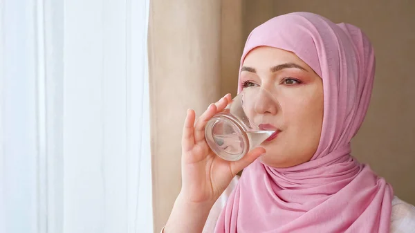 Wanita muda dalam jilbab minum air dari gelas — Stok Foto