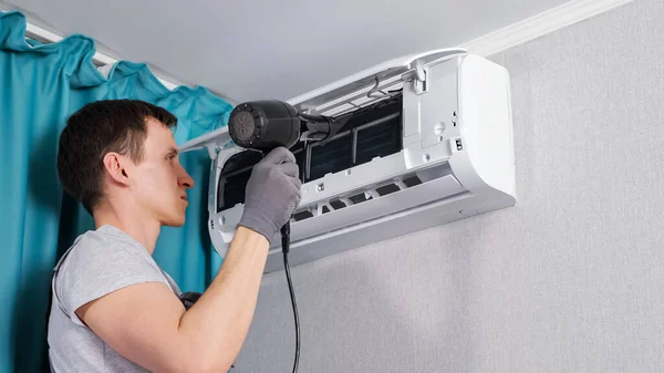 Koncentrovaný údržbář čistí klimatizaci sušičkou — Stock fotografie