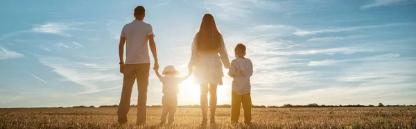 Família com crianças caminha ao longo dos campos ao pôr-do-sol — Fotografia de Stock