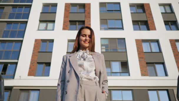 Mujer joven en un traje de negocios desciende las escaleras en el fondo del edificio, cámara lenta — Vídeos de Stock