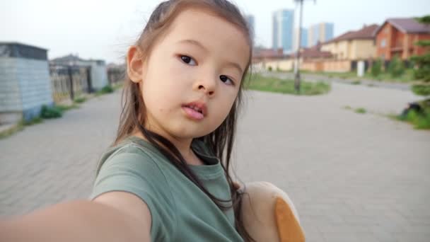 Hübsches kleines asiatisches Mädchen mit Hund macht Selfie auf Böschung — Stockvideo