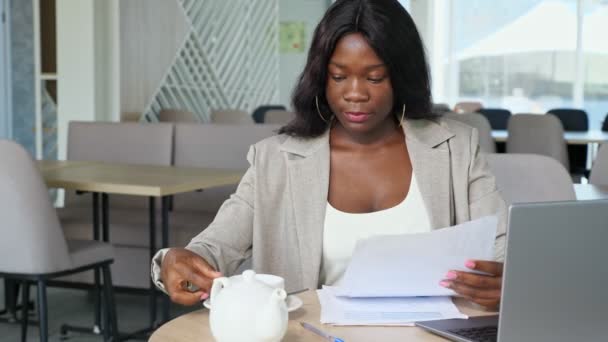 Svart forretningskvinne drikker te mens hun leser aviser på kafeen – stockvideo