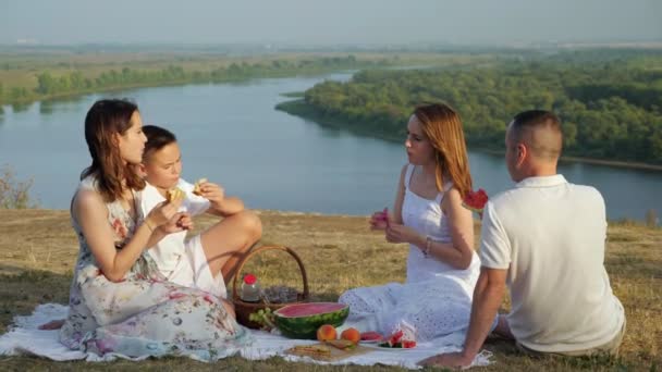 Flicka och pojke äter smörgåsar med föräldrar på festlig picknick — Stockvideo