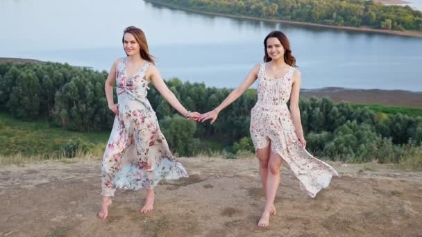 Mulheres muito descalças em vestidos posar na colina contra o rio — Vídeo de Stock