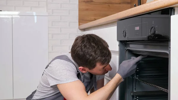 Pracovník otočí páky kontrolu rozbité trouby v prostorné kuchyni — Stock fotografie