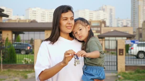 Cheerful woman shows keys of apartment holding daughter — Stock Video