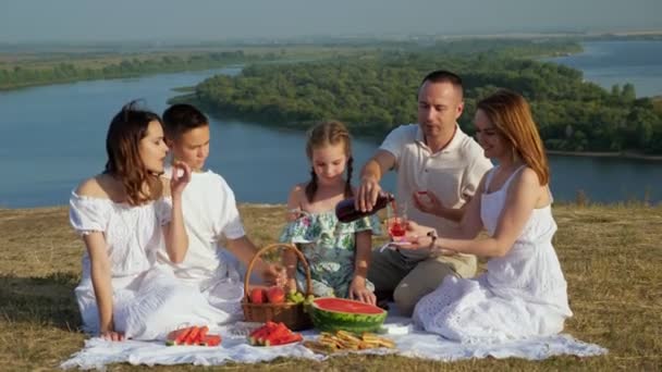 Hombre vierte bebida en esposa vidrio niños comer uva en el picnic — Vídeos de Stock