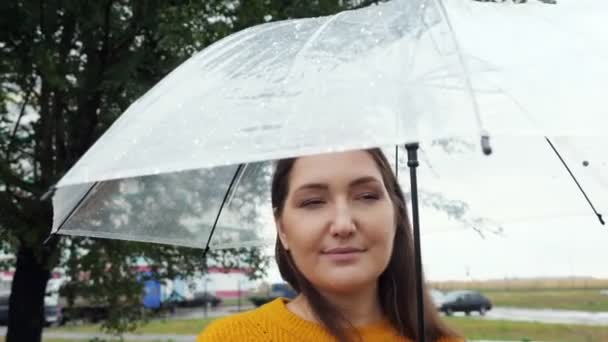 Close-up de uma mulher sob um guarda-chuva transparente em tempo chuvoso — Vídeo de Stock