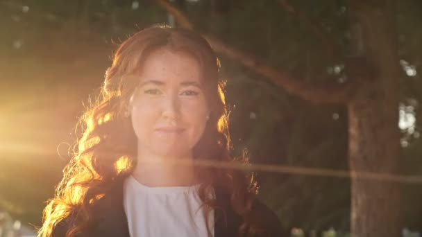 Šťastná žena s kudrnatými vlasy a pihami stojí při západu slunce — Stock video