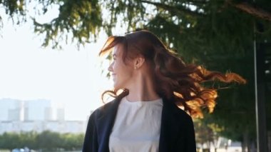 Mutlu kadın modern şehir sokaklarında uzun kıvırcık saçlarını sallıyor.