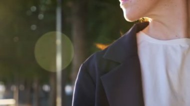 Ceketli kadın şehir caddesinde duran bakır saçlarını sallıyor.