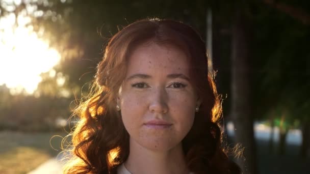 Mulher feliz com cabelo encaracolado e sardas fica ao pôr do sol — Vídeo de Stock