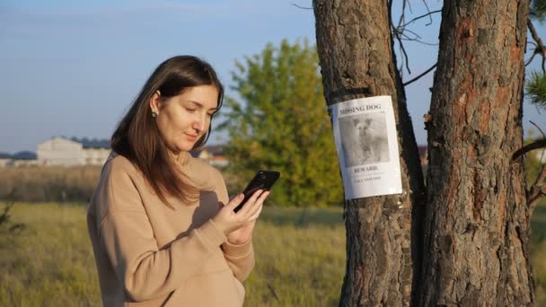 Parktaki kayıp köpek posterinden kapüşonlu kadın arama numarası. — Stok video