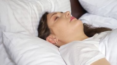 Genç kadın uyanıyor ve kameraya gülümsüyor.