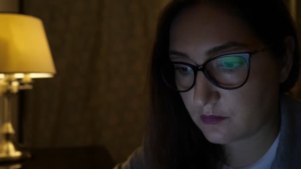 Close-up van een vrouw met bril werken op een laptop in het donker — Stockvideo