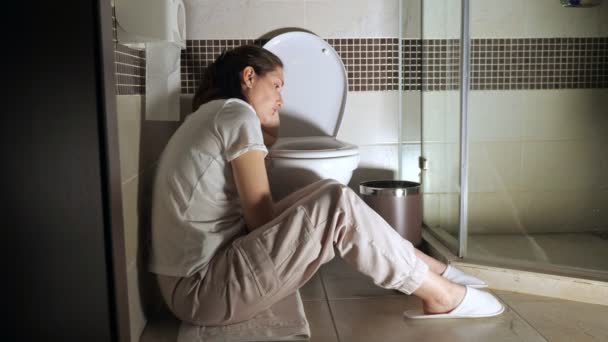 Молода жінка сидить біля туалету — стокове відео