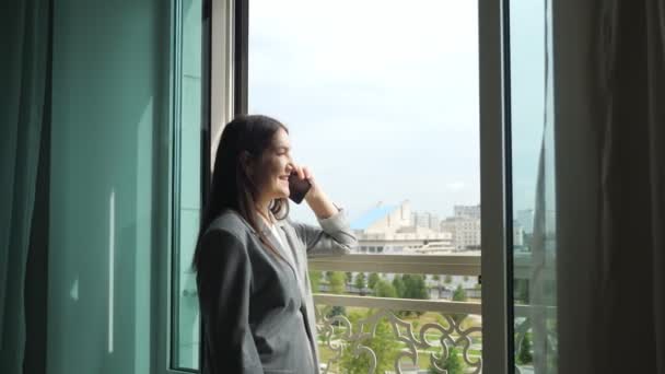Young woman in business suit talking on the phone by the open window — Stock Video