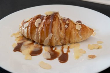 Ev yapımı kahvaltı için beyaz tabakta karamelli ve şuruplu kruvasan.