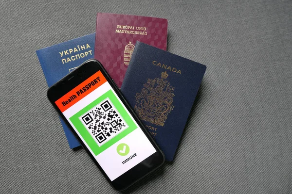 Gri arka planda akıllı telefon dijital sağlık pasaport uygulaması ve üç pasaport ile seyahat covid-19 bağışıklık sistemi