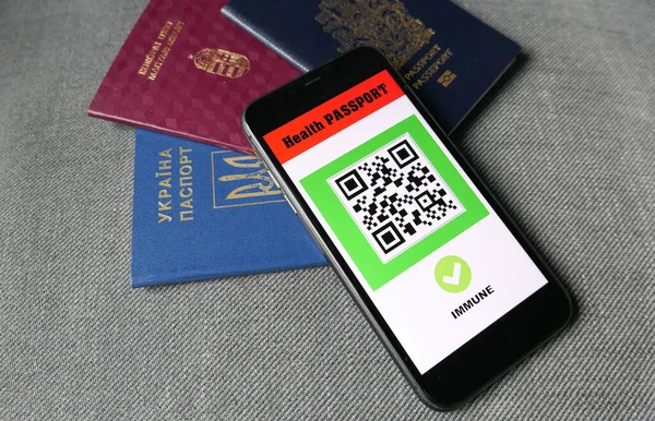 Gri arka planda akıllı telefon dijital sağlık pasaport uygulaması ve üç pasaport ile seyahat covid-19 bağışıklık sistemi