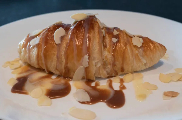 Pečený Croissant Karamelem Sirupem Bílém Talíři Domácí Snídani Mandlí — Stock fotografie