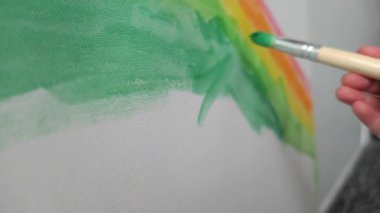 Çocuk gökkuşağıyla renkli çizgiler çiziyor.