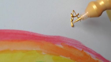 Çocuk gökkuşağıyla renkli resimler çiziyor.