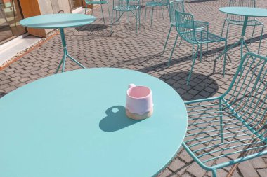 Pembe kupa mavi masa kafeteryasında. Kahve saati dışarıda.