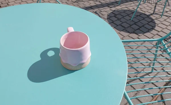 Pembe kupa mavi masa kafeteryasında. Kahve saati dışarıda.
