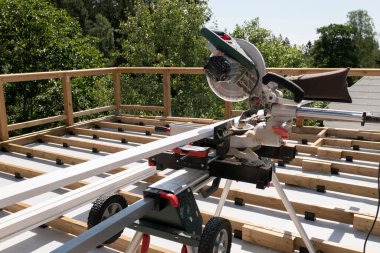 Yeni bir ev inşa projesinin tahtalarını kesmek için el yapımı solucan sürücüsü kullanan müteahhit işçi.